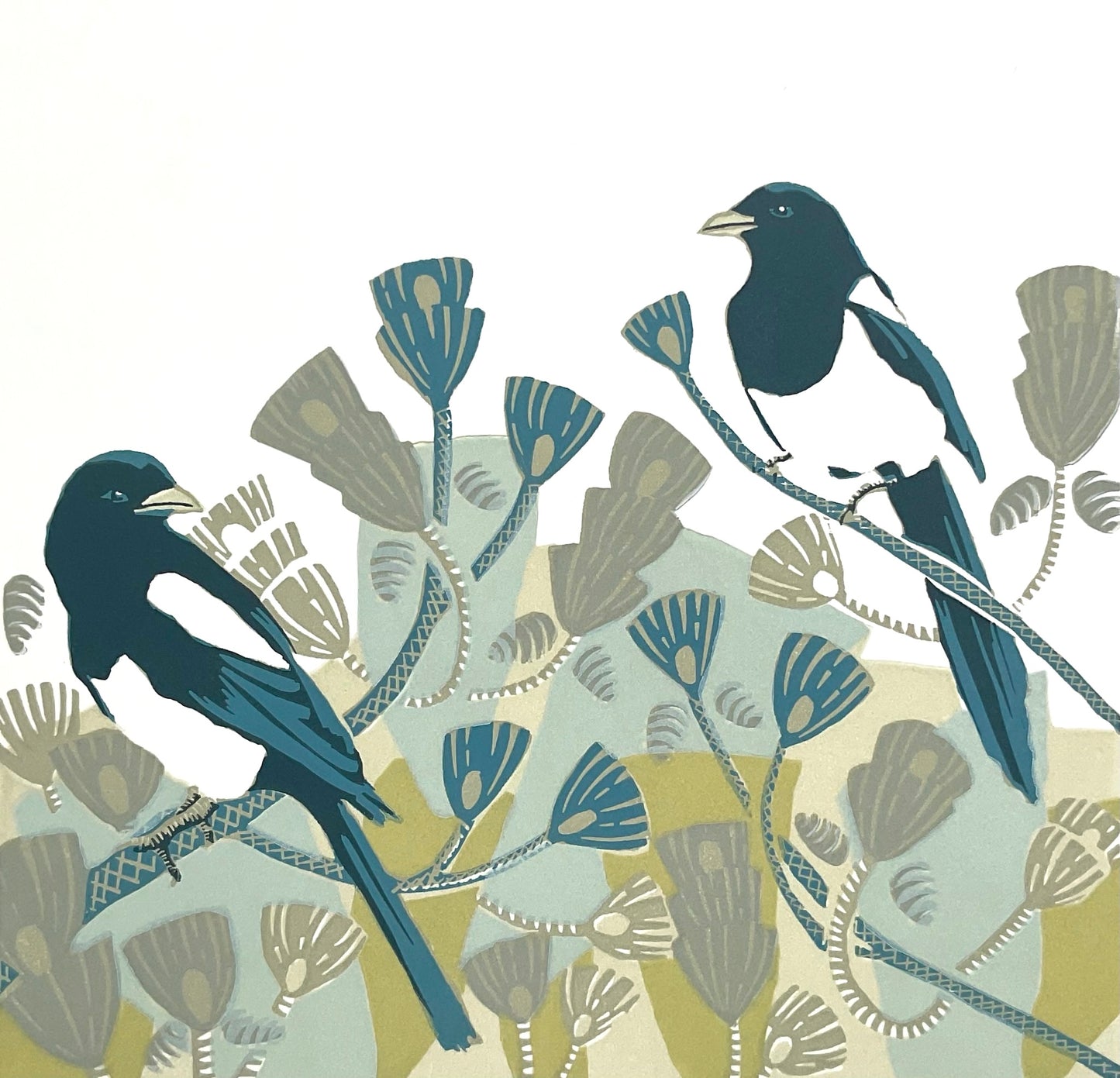 a pair of magpies are shown sitting among pine tree branches in a modern style. The foliage of the tree is shown using bold geometric shapes using airforce blue, olive green, duck egg blue, beige, and pale sand colours. The design is simple and striking and the inky coloured magpies stand out against the white of the paper.