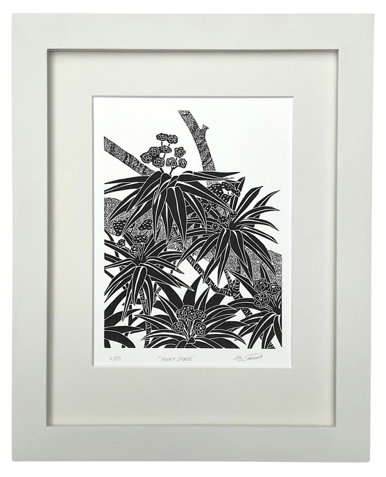 A modern style black and white print in a bold slightly tribal style showing part of a Honey Spurge plant in close up. Five groups of leaves and flowers are shown atop the woody stems and a branch of a tree is shown running diagonally across the picture as a backdrop.  An off white mount surrounds the print with a matching painted wooden frame. 